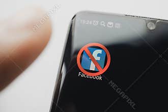 A crossed-out icon on a black smartphone screen. concept of banning the application facebook