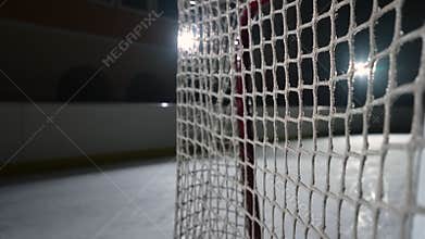 The hockey puck hits the net, scored a goal. Close up of a slow motion hockey puck flying into the net. Cinematic behind
