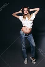 Smiling pregnant female with big earphones on tummy.