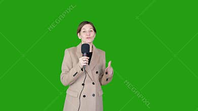 GREEN SCREEN CHROMA KEY Caucasian female TV news reporter in coat holding microphone talking against green background.