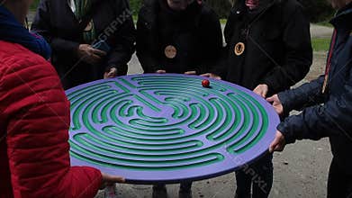 People playing labyrinth game in forest trial. Team building activity.