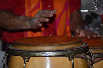 Closeup of a person playing an African music instrument called a bongo