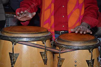 Closeup of a person playing an African music instrument called a bongo