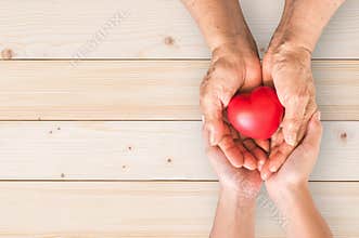 Elderly senior or grandparent's hands with heart in support of nursing family caregiver for national hospice palliative care