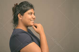 Young overweight beautiful Asian woman against gray background