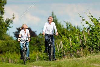 Happy senior couple cycling outdoors in summer