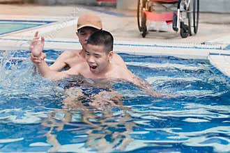 Strong arm muscles of Asian special child on wheelchair with swimming