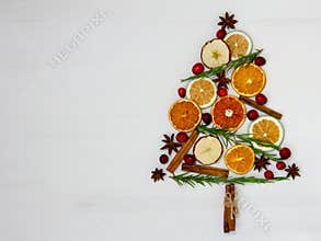 Christmas tree of food on a white background. Ingredients: cranberry, rosemary, orange, apple, lime, cinnamon and anise. Top view