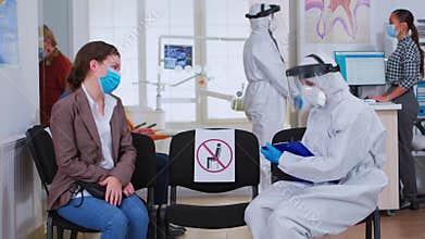 Dentist nurse with protection equipment talking with patient
