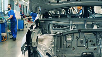 Car manufacturing worker assembling a car body on an assembling line