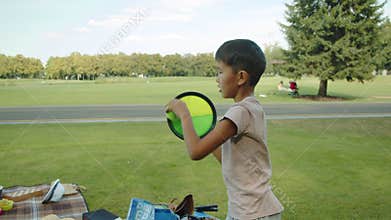 Little asian boy in the park catches a tennis ball, sports, summer, sunny, outdoors in the background