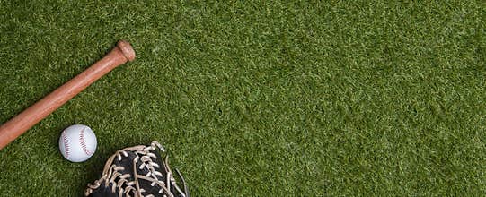 Baseball bat, glove and ball on green grass field.  Sport theme background with copy space for text and advertisment