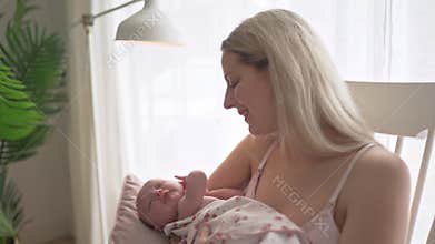 Mother holding newborn baby in chair