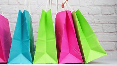Multicolored paper shopping bags on white brick wall background