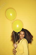 Young African-American woman holding balloons.