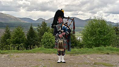 The real McCoy traditional Scotland Bagpipes singer, in the landscape of highlands