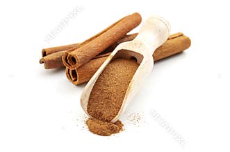 Taste enhancing and flavour spice concept with wooden scoop with fine powder and cinnamon sticks isolated on white background