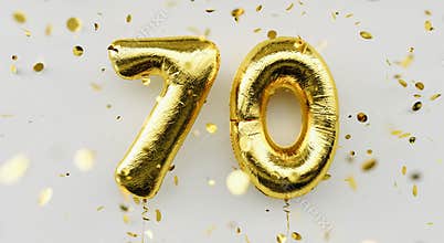 70 years old. Gold balloons number 70th anniversary, happy birthday congratulations, with falling confetti on white background