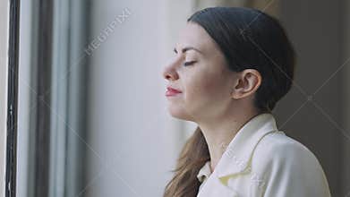 Side view face of relaxed young woman enjoying tea at lunch break looking out the window. Close-up portrait of happy