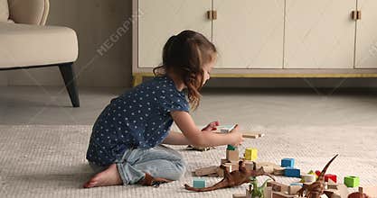 Small girl build with wooden cubes in living room