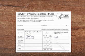 Close up isolated image of a COVID 19 vaccination record card on a wooden desk