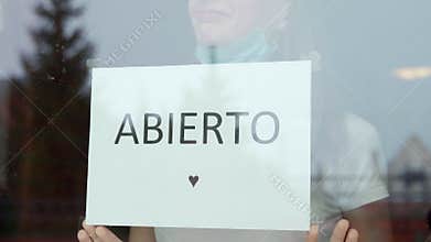 Woman stickers Abierto re-opens after the end of the coronavirus quarantine in the cafe the coffee shop is ready for