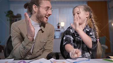 portrait of family during an online lesson, girl writes in a notebook and then gives five to her father, parent and