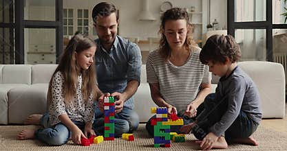 Young couple and kids play colorful blocks at home