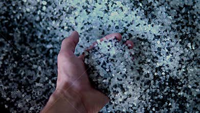 Plastic black and white granules are poured from the hand. Plastic granules, dye, polymer granules are used for the
