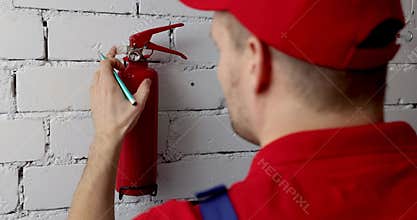 Fire safety and prevention - service engineer checking extinguisher condition and writing documents