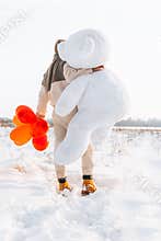 Young man from behind hugs holding big teddy bear soft toy gift heart air balloons on this special day surprising girlfriend. roma