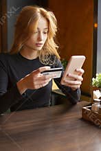 Woman making card payment through mobile phone to pay bills. Vertical photo.