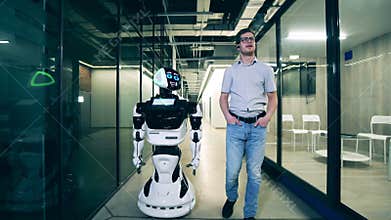 Businessman is chatting to a cyborg while walking along the hall