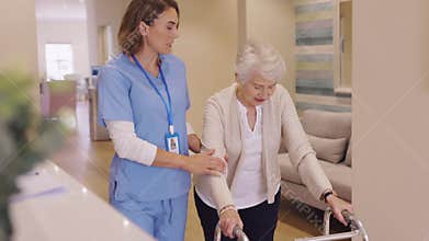 Nurse helping senior woman to walk at private clinic