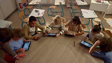 Male teacher helping students with tablet computers at lesson.