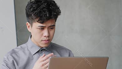 Portrait of pensive Asian business man working with laptop solves application problems error in network. Thoughtful