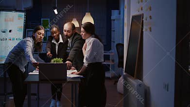 Multi ethnic businesspeople analyzing management presentation using laptop computer