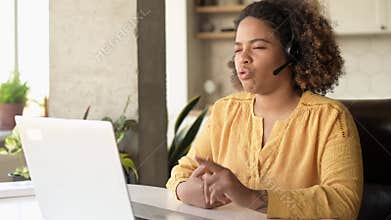 Helpful biracial woman wearing headset using laptop computer for video connection