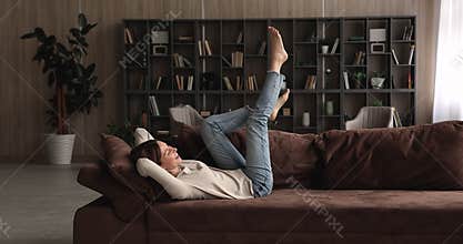 Carefree woman enjoy weekend sing song lying on cozy couch