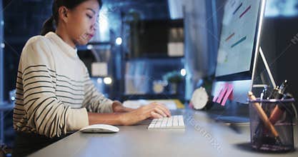 Asian business woman typing keyboard and click mouse, work late night using desktop computer in home office