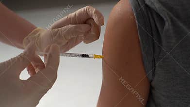 Close-up of doctor in medical latex gloves giving injection vaccine against coronavirus during mass vaccination campaign