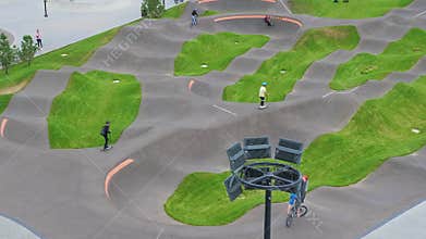 Children ride bicycles, scooters in skatepark