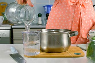 Woman hands pouring water in saucepan measuring jug to cook boil food, dish.