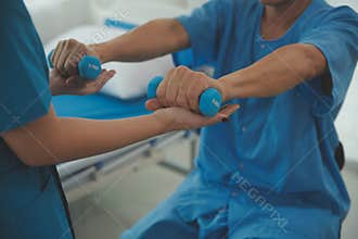 Physiotherapist man giving exercise with dumbbell treatment About Arm and Shoulder of athlete male patient Physical therapy