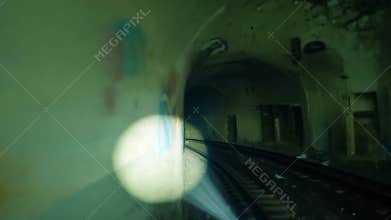 Flashlight illuminating abandoned train station tunnel