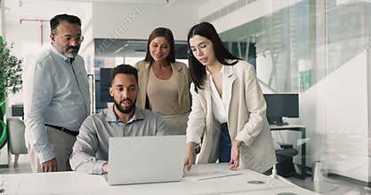 Team of four multiethnic colleagues learning new software using laptop