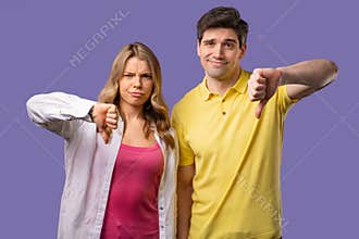 Young couple with sign of dislike. Stylish man and woman, thumbs-down, dont like