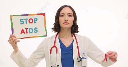 Woman doctor shows sign with phrase Stop AIDS and red ribbon