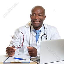 African doctor on a desk with glasses in his hand