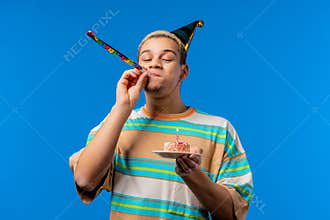 Happy birthday man making wish - blowing candle on cake. Curly haired guy
